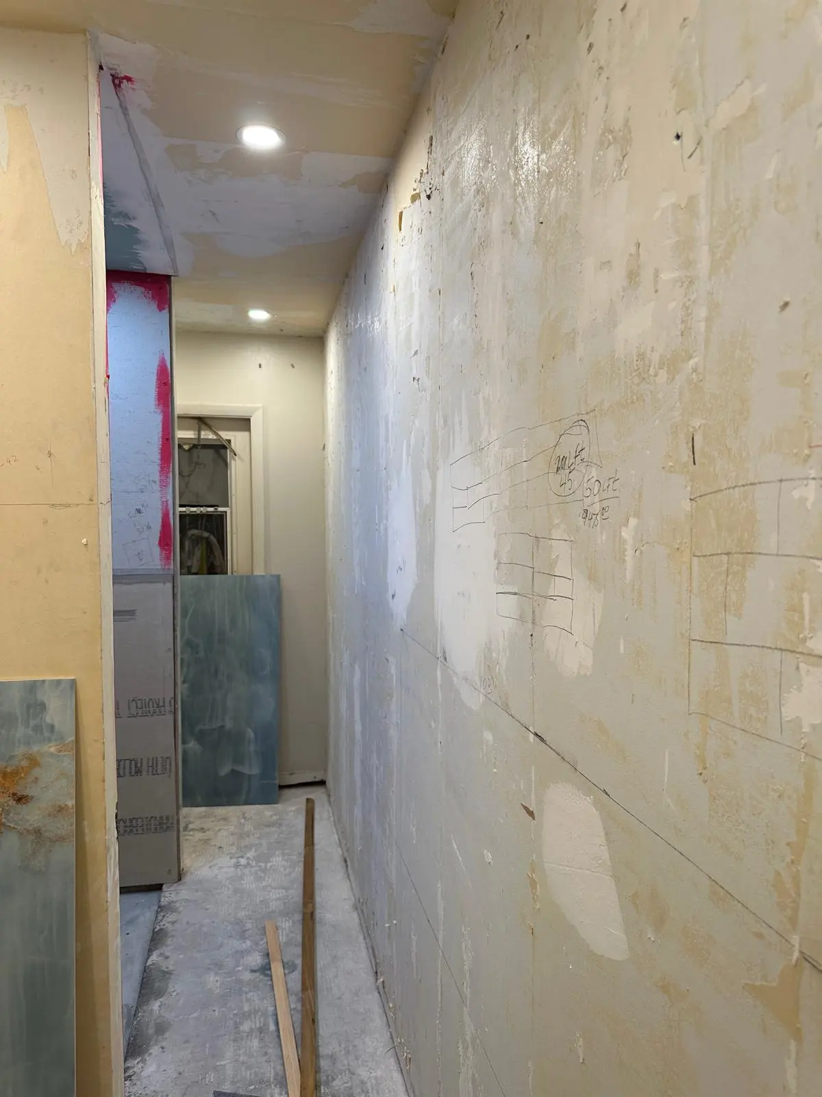 Skim-coat plaster repair in progress in a hallway